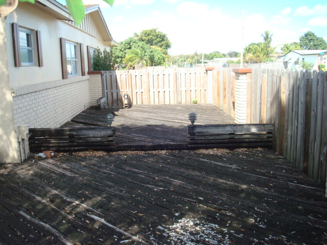 EAST SIDE OF HOME LOOKING NORTH WITH WOODEN DECK THAT NEEDS TO BE REPLACED