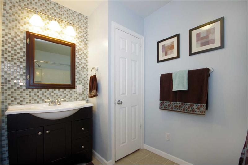 Large, full bath on the main level with a beautiful vanity, glass tiles, tile flooring, and linen closet.