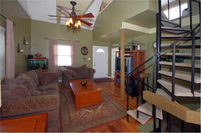 Spacious living room with vaulted ceilings, ceiling fan, and hardwood flooring