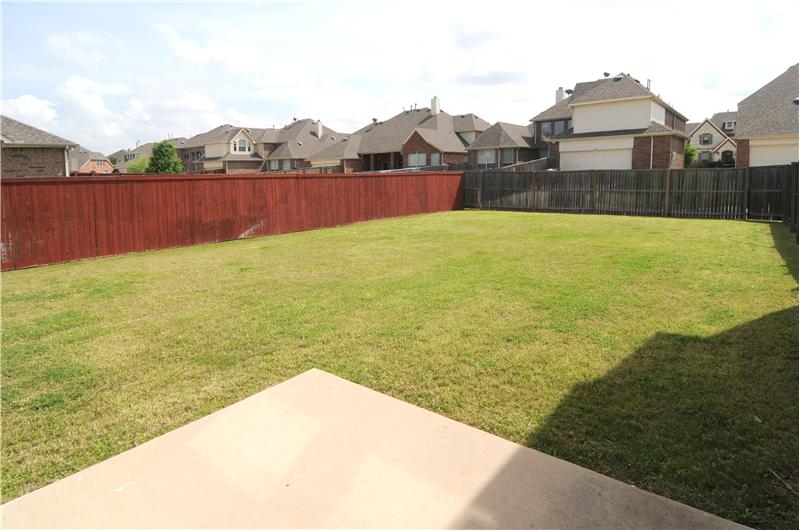 The spacious yard is surrounded by a wood fence.