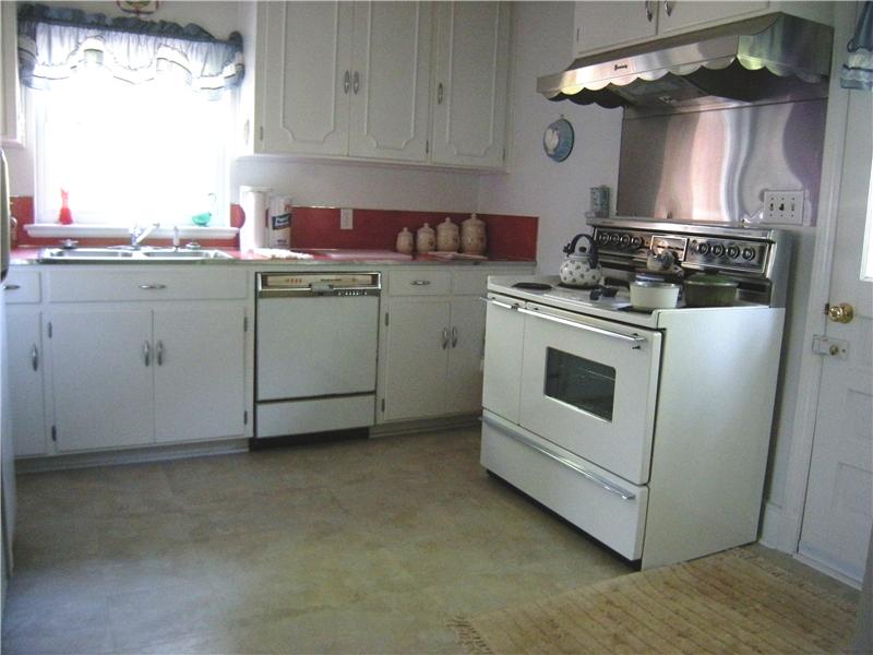 Kitchen has an electric cooktop oven with hood, double sink & cabinetry