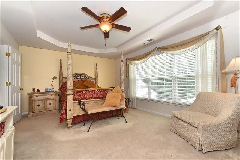Spacious master bedroom has a trey ceiling, wall to wall carpeting and sitting area