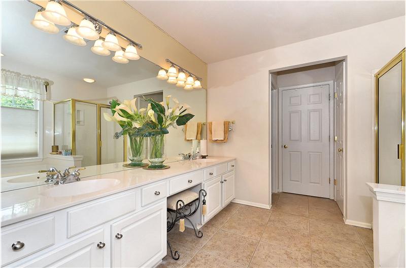Master bathroom has dual vanities, custom cabinetry and spacious walk-in closet