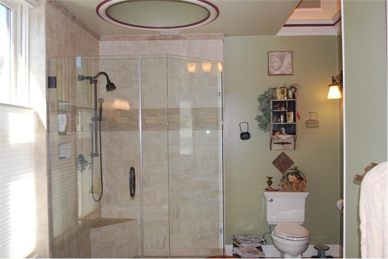 Stone Tile Accents the Walk in Glass Surround Shower